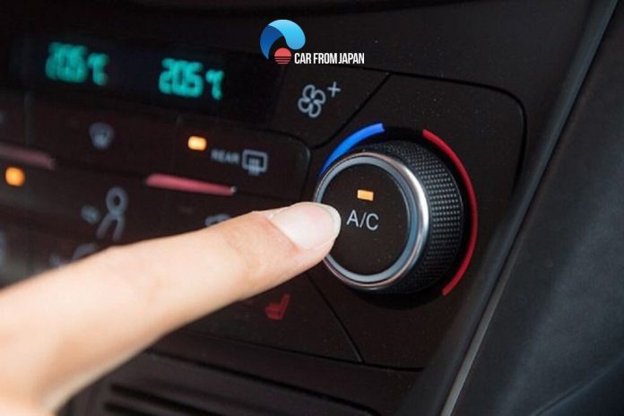 Finger pressing the car AC button on dashboard