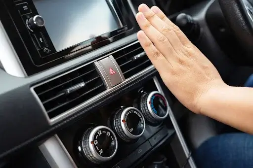 Hand in front of car air conditioning vent