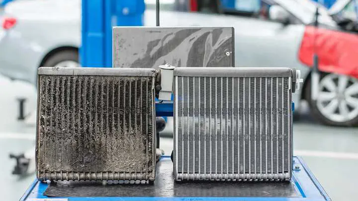 Dirty clogged car radiator core beside a clean new radiator core